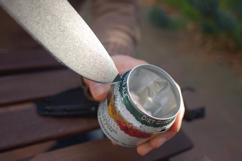 Using weight of knife to create vent hole in pop can stove.